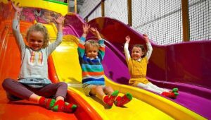 Children enjoy colorful slide in indoor play area.