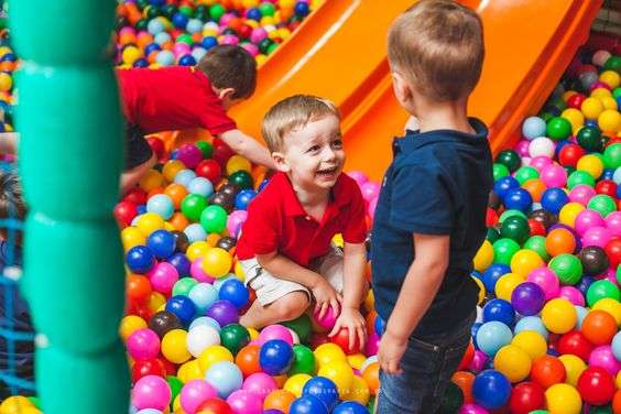 Playful boys enjoying themselves in a ball pit filled with colorful balls.