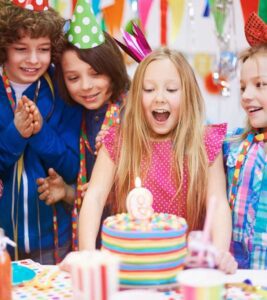 A joyful group of children celebrating their birthday, gathered around a cake adorned with candles.