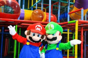 Two Mario Bros characters smiling and posing for a photo in a play area, showcasing their playful and adventurous spirit.