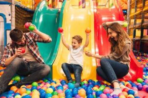 A joyful family playing in a colorful ball pit at a children's play center, creating cherished memories.