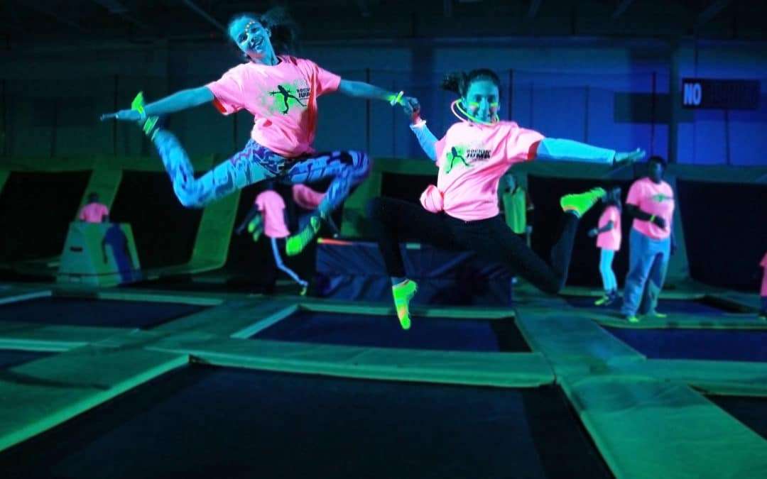 Trampoline fun with two people in bright neon shirts.
